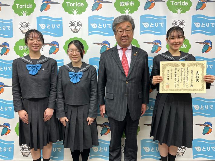受賞者と市長の集合写真。右から賞状を持つ制服姿の女子生徒、市長、女子生徒2名