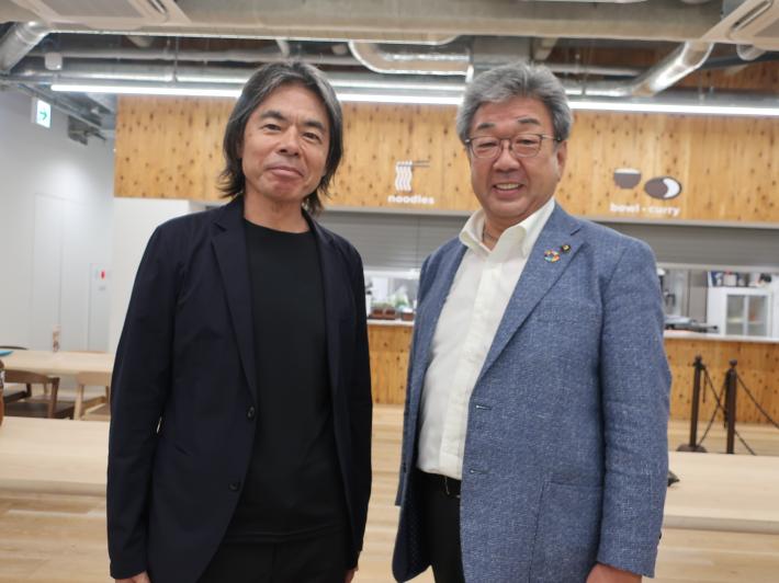 東京藝術大学との連携協定の様子。スタジオ様の場所で男性が2人で並び記念撮影している。