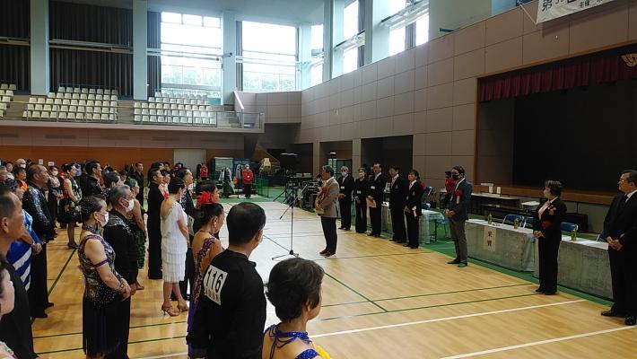体育館ステージ前で挨拶をする市長と衣装を着用した選手達