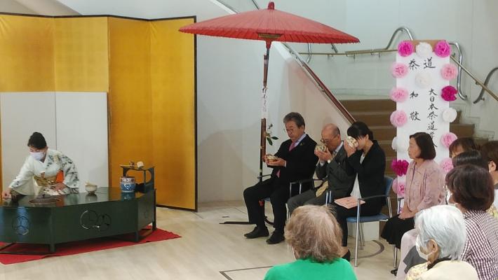 ホールのエントランスにてお茶をたしなむ市長。左には金屏風の前でお茶を点てる着物の女性