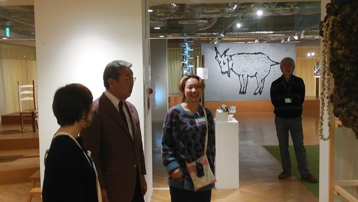壁に展示された作品を見る市長と出展者。奥の壁にはヤギの絵