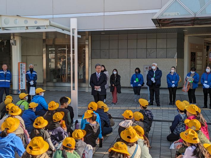 黄色の安全帽を被った児童の前で挨拶をする市長