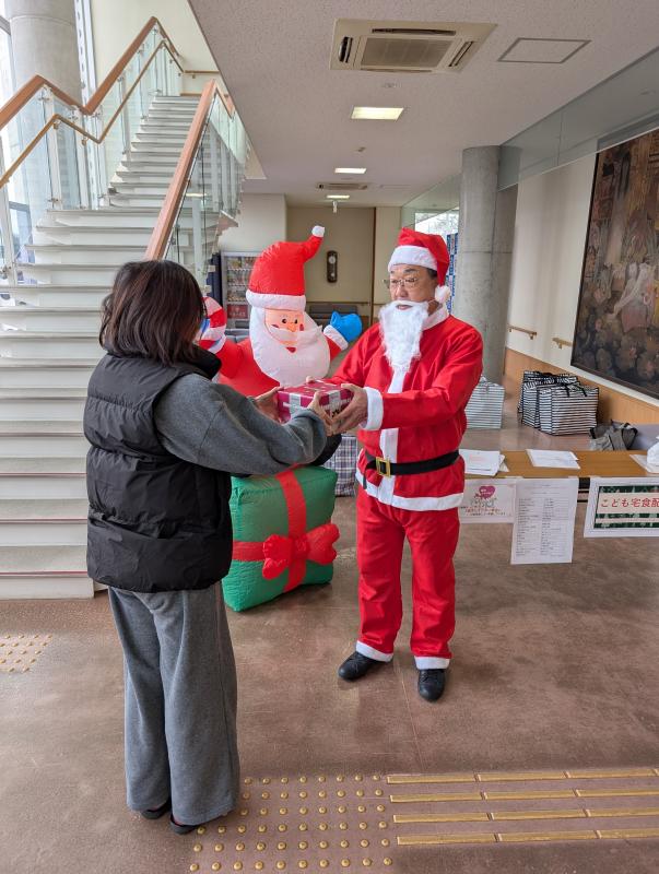 サンタの服を着た男性がプレゼントを渡している