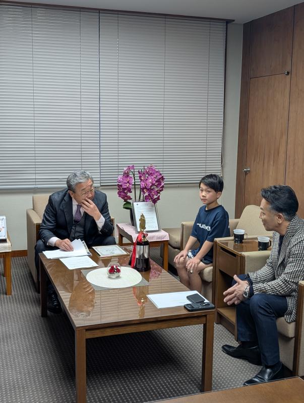 アームチェアに腰かける男性2名と小学生