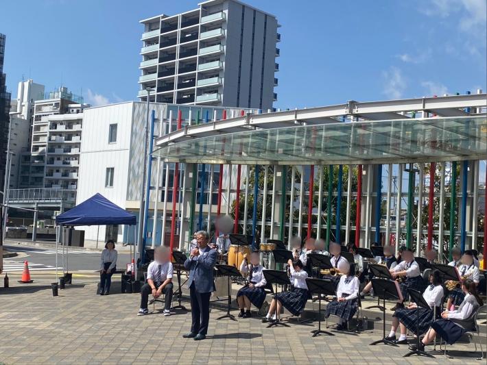 演奏をする人たちの前で挨拶をする男性