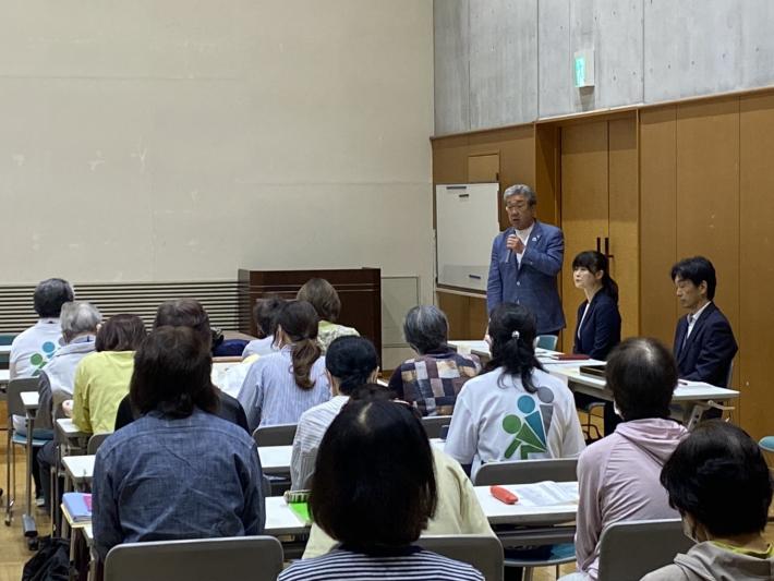 話をする男性とそれを聞く人々