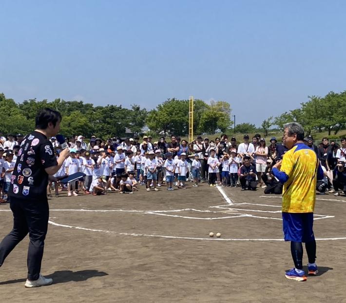 グラウンドに立つ大勢のこどもたちと男性