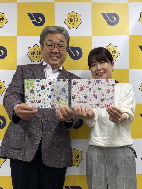 母子手帳カバーを持って笑顔をむける男性と女性