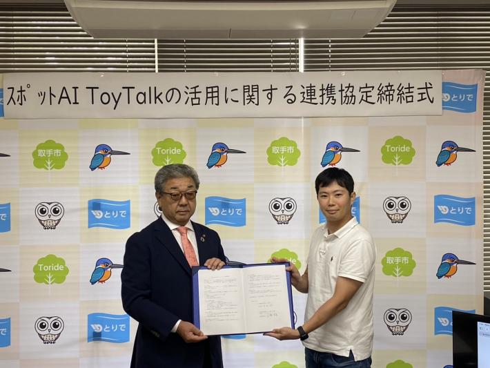 取手市のパネルの前で証書を持って並ぶ男性二人