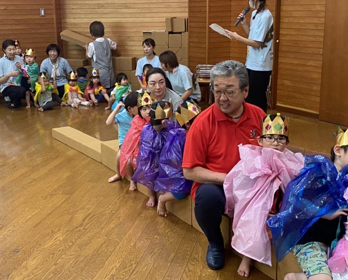 段ボールの列車に乗る王冠をつけた子供たちと男性