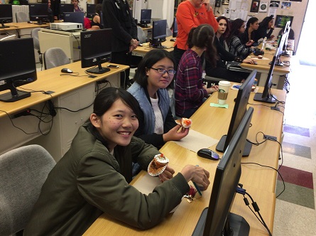 日本人学生2名がパソコンの置いてある机でお菓子を食べている様子