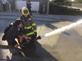 消防署員の指導を受けながらホースで放水をする女性の派遣団学生