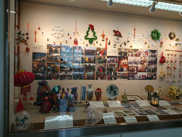 藤代駅市民ギャラリーのショーケースに写真や作品が並べられている様子。左側にはさおりをりのアマビエが配置されている。