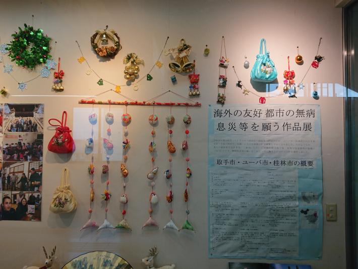 藤代駅市民ギャラリーのショーケースに作品が飾られている様子。壁左側にはつるし飾りが配置されている。
