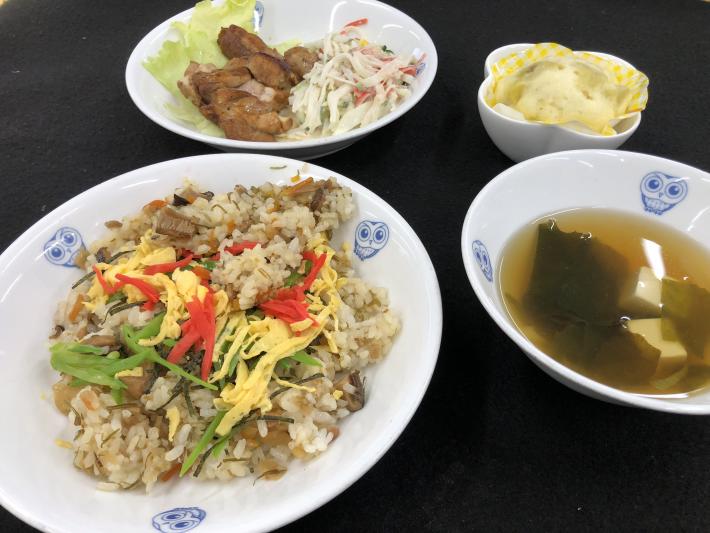 ふくろう柄の絵皿に盛られるちらし寿司、大根のサラダ、鶏肉、スープ。