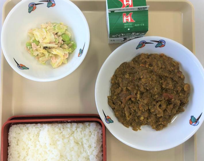 根菜カレー、米飯、牛乳、サラダがお盆に載っている