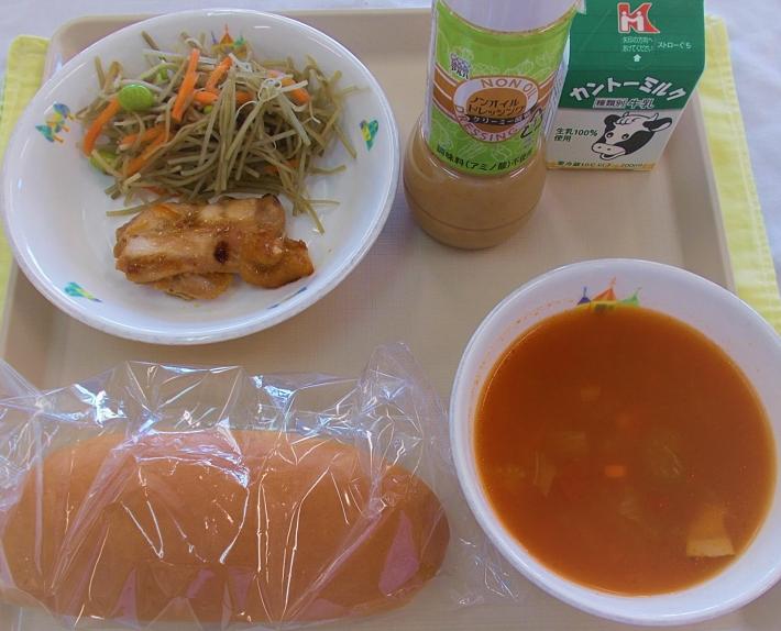 赤いスープ、包装されたパン、鶏肉の焼き物、ごぼうサラダ、ドレッシング、牛乳がお盆の上に載っている。