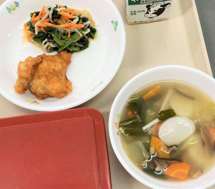 皿に盛られた揚げ肉と小松菜や人参の和えたもの。餅や人参、小松菜が入ったスープもお盆にのせられている。