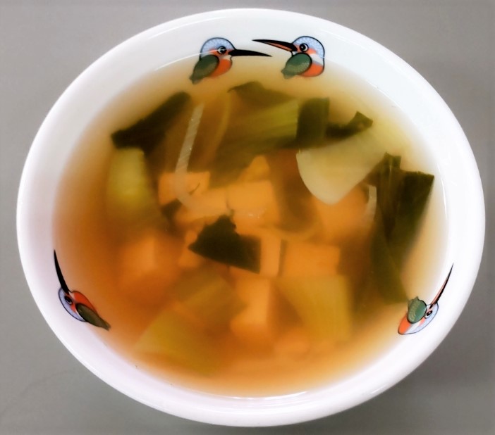 白い陶器に盛られた豆腐スープ。チンゲン菜や豆腐が入っている。