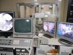 多数のモニターや機械の置いてある検診台の隣の部屋の画像。