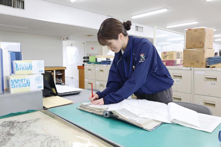 女性職員が机の上にある地図に赤線を引いている写真