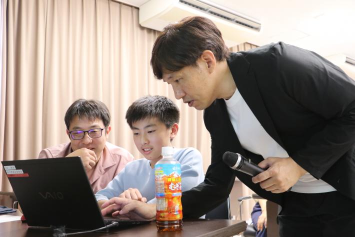 株式会社Bot Expressの社員の男性が親子に操作を教えている