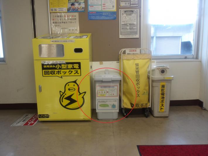 取手庁舎の回収場所の写真。黄色い小型家電回収ボックスや電池回収箱の並びに赤丸で示された回収ケースがある