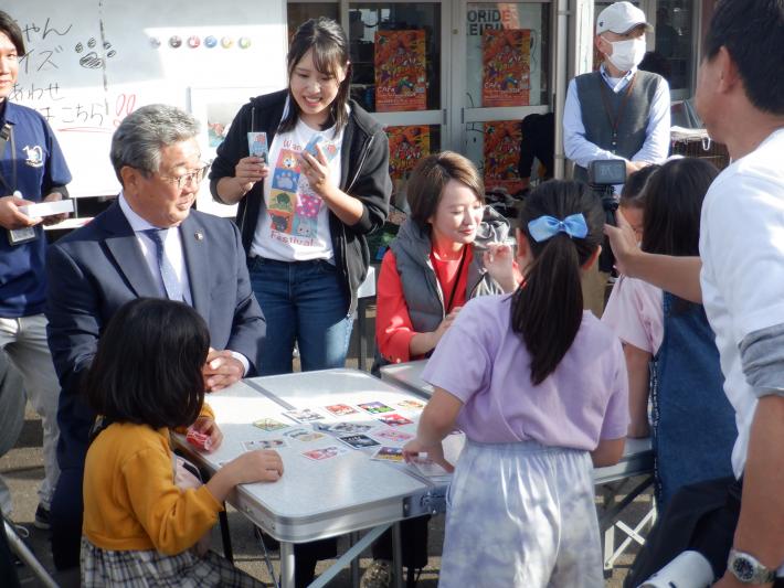 犬猫カルタ大会の様子。机の周りに1人の男性と2人の女性と3人の子どもが取り囲みカルタをしている