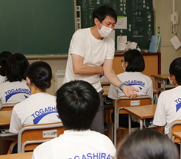 杉浦先生が教壇から着座している生徒の列を歩いて語りかけている