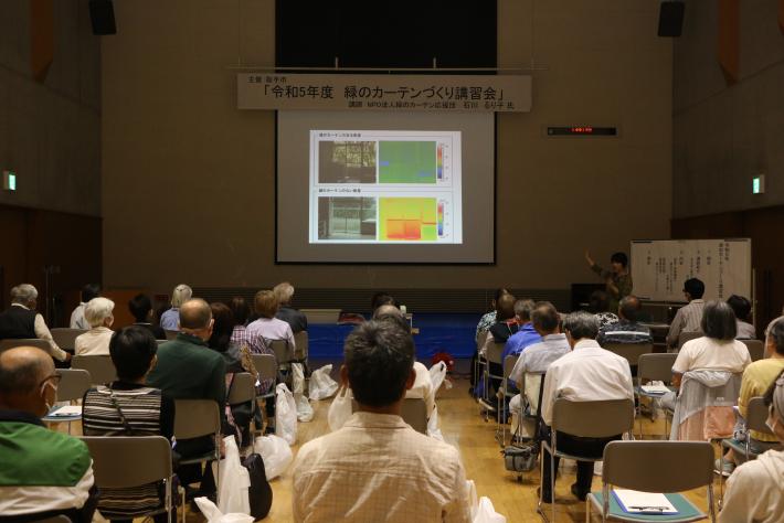 緑のカーテン講習会の会場全体が写った写真。スクリーンには講習会の内容が映し出され、参加者は正面のスクリーンを向いて座っている