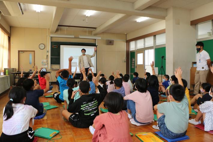 講師の質問に手を上げている小学生の後ろ姿