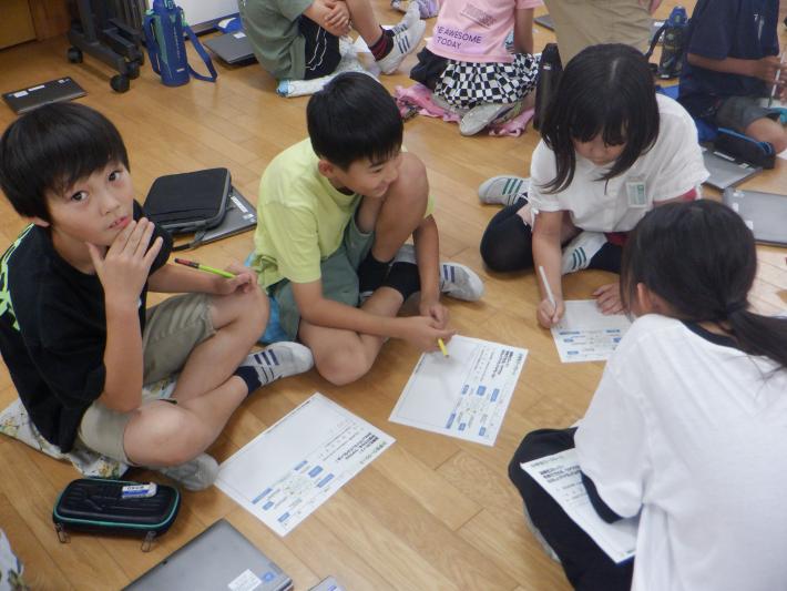 話し合いながら教材のプリントに書き込んでいる4人のこどもたち