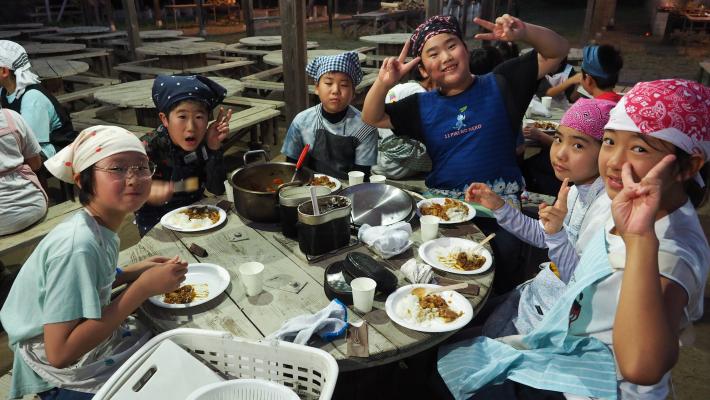 みなかみツアーにて飯ごう炊飯後に子ども達がカレーを食べている様子