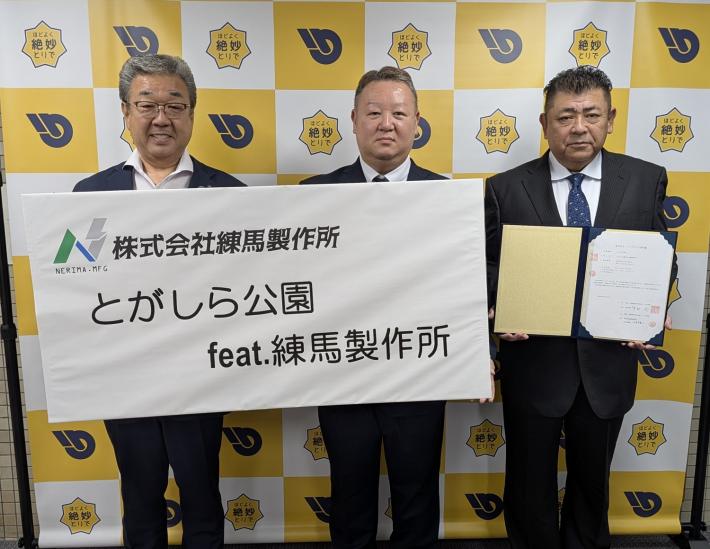 とがしら公園フューチャリング練馬製作所と書かれたボードを持つ市長と練馬製作所社長