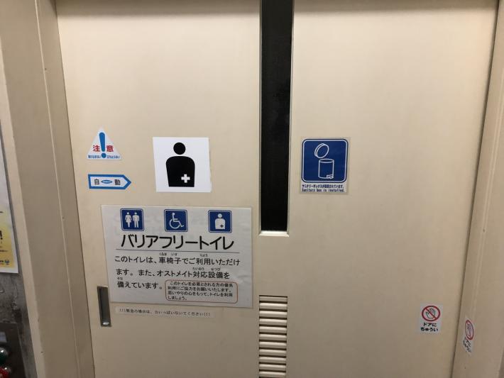 トイレの入口にサニタリーボックスが設置されている事を表示するピクトグラムが映っている写真です