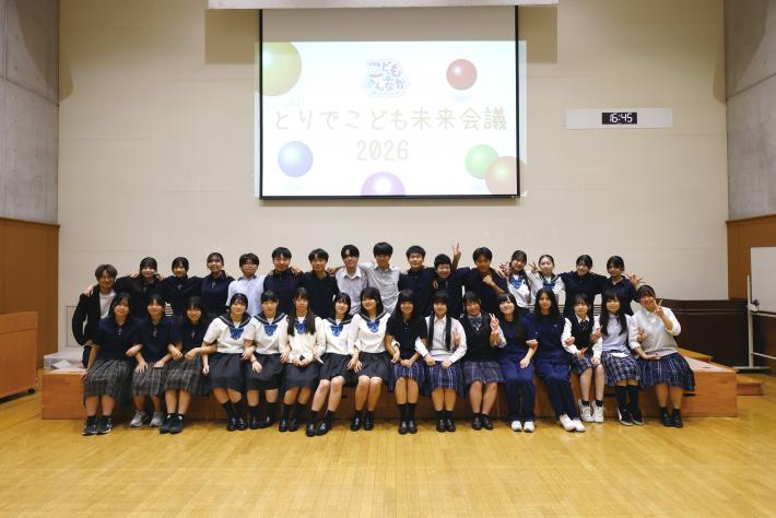 32人の高校生が「とりでこども未来会議2026」と投影されたスクリーンの前に並んだ集合写真