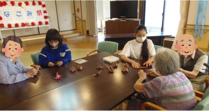 和祭（なごみまつり）で高齢者のかたがたと折り紙を一緒に折る様子