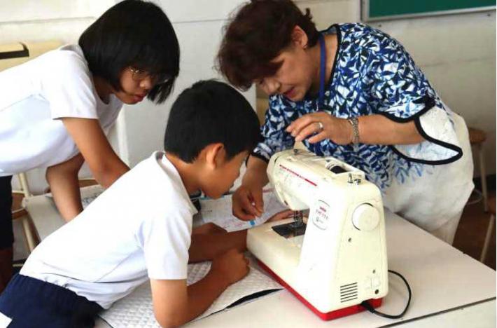 ボランティアのかたにミシンを熱心に教わる様子