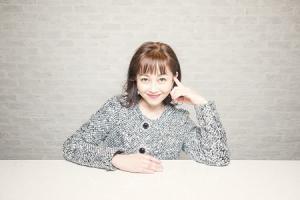 テーブルに手を付き微笑む女性（浅香唯さん）