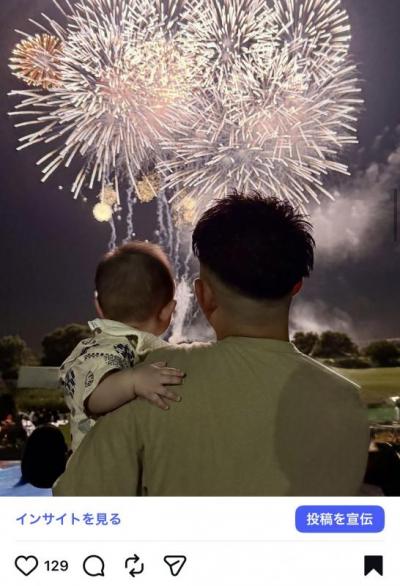 いいね賞4位の写真。父親が赤ちゃんを片手に抱いて花火大会を見ている後ろ姿の写真。