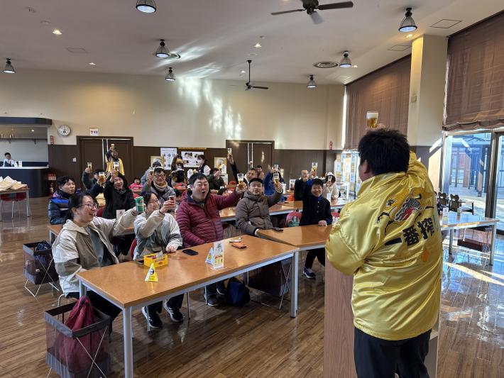 一番搾りのジャケットを羽織った男性が乾杯の音頭をとっている様子