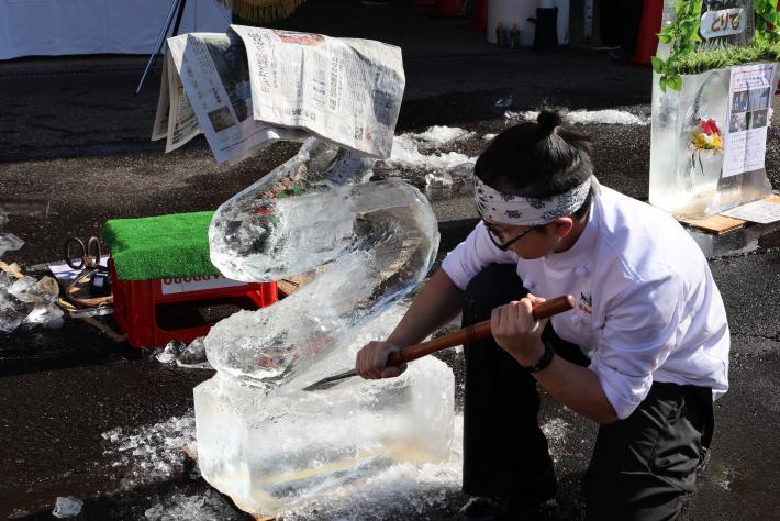 男性が氷彫刻でへびを作っている様子