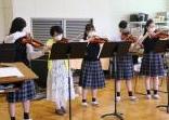 バイオリンを演奏する若い女性と学生達