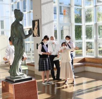 像のあるホールで3、4人の人が額を集めて話しをしている写真。