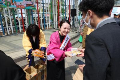 ステージで市内企業提供品を来場者に配布するさくらまやさん