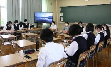 放課後ワークショップの写真。前方黒板横にテレビが置かれた教室で生徒がコの字型に座って話し合っている写真。