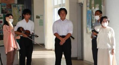 男子生徒と先生、若い女性が廊下に立っている写真。
