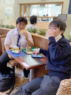 お茶とパンで休憩をとっている若い男性2人の写真