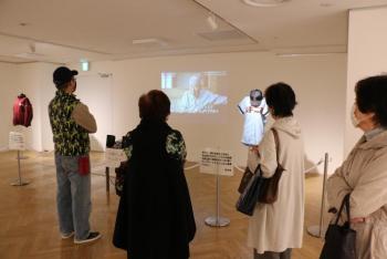 木内幸男氏追悼記念展で壁に映し出されている動画を4名の人が見ている様子の写真