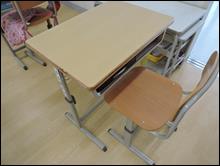 小学校の教室内に置かれた一組の机と椅子を上側から撮影した写真